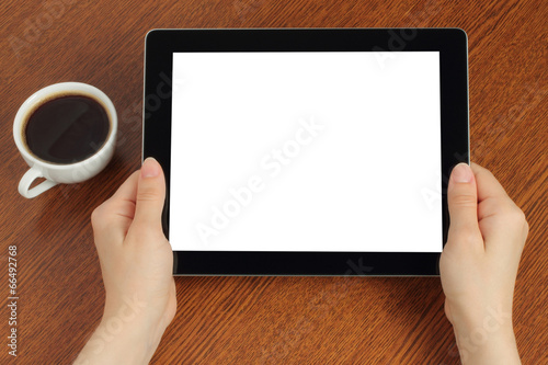 Hands hold tablet PC on wooden background .