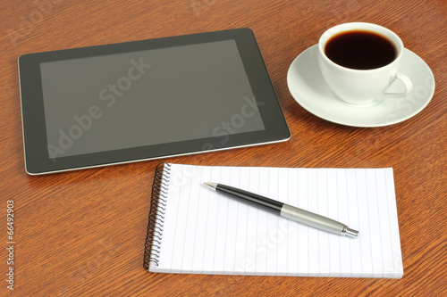 Tablet PC  notepad  pen and cup of coffee on wooden background .