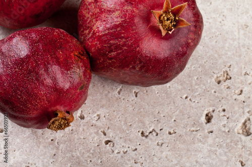 Freshly picked pomegranates on a travertine tile - great background for card or stationary photo