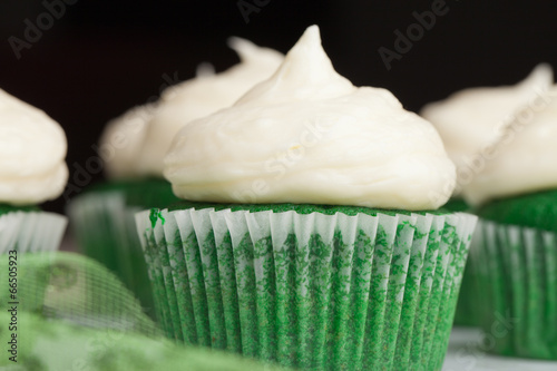 Macro shot of St. Patrick's Day green velvet cupcakes piped with a decadent cream cheese frosting - think red velvet cake green!