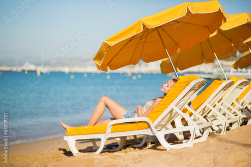 Fototapeta Naklejka Na Ścianę i Meble -  Girl relaxing on a beach chair near the sea