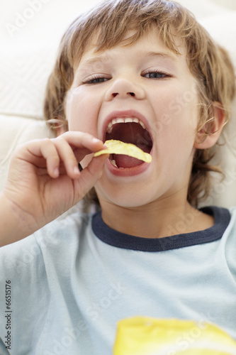 Young boy eating crisps