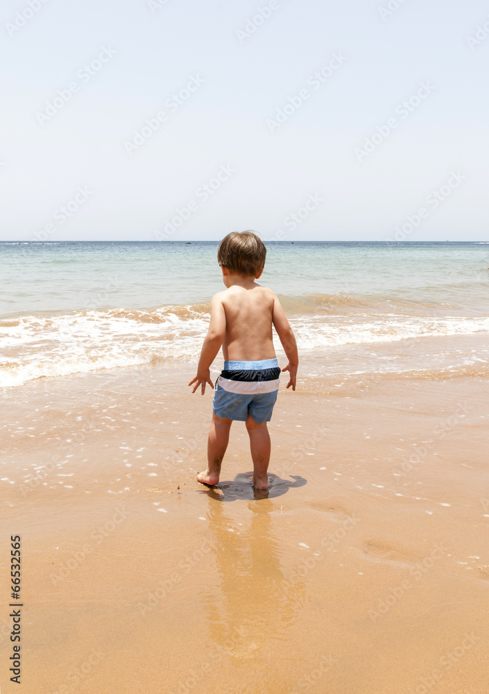 Beautiful young boy playing at the beach in a sunny day Beautiful young boy playing at the beach in a sunny day