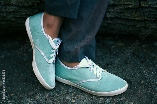 Azure sneakers on womens feet in park closeup