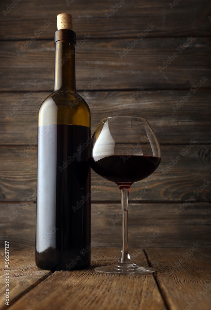 Bottles of wine with glass on wooden background