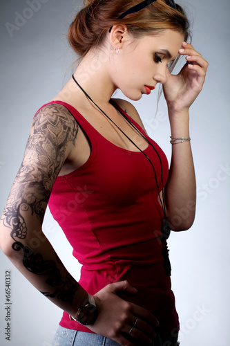 Молодая девушка в красной майке с татуировкой