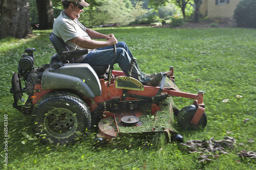 Landscaper cutting grass on riding lawn mower