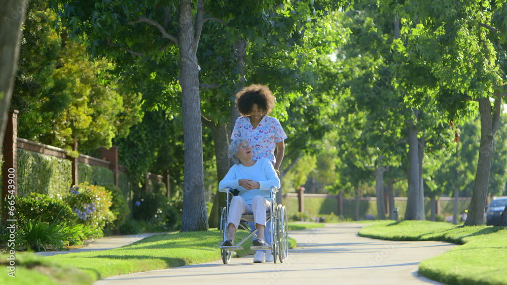 Nurse walking with elderly woman in wheelchair Nurse walking with elderly woman in wheelchair