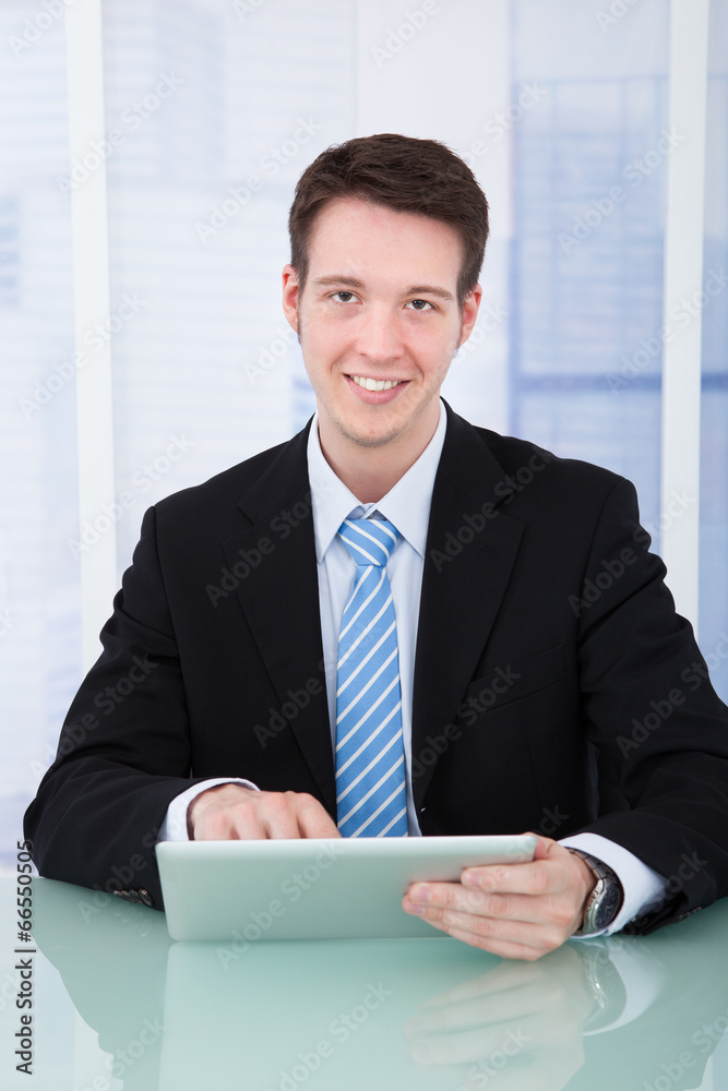 Confident Businessman Using Digital Tablet At Desk Confident Businessman Using Digital Tablet At Desk