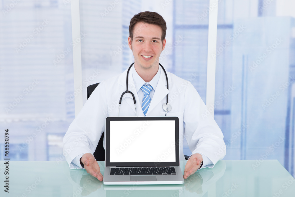 Doctor Presenting Laptop With Blank Screen At Desk Doctor Presenting Laptop With Blank Screen At Desk