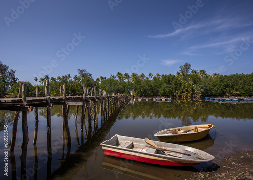 Fototapeta Naklejka Na Ścianę i Meble -  fishing boat parked under palm tree and blue sky as a background