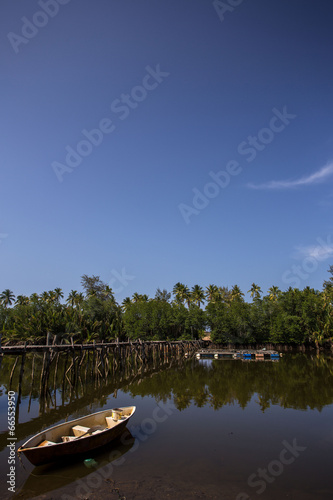 fishing boat parked under palm tree and blue sky as a background © suhaimihassan