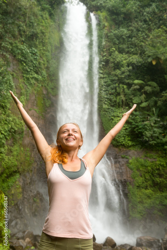 Young woman practicing yoga by the waterfall