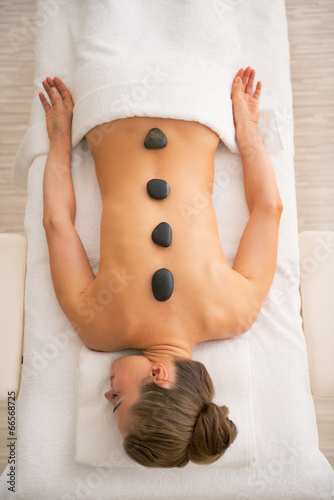 Relaxed woman laying on massage table and receiving hot stone