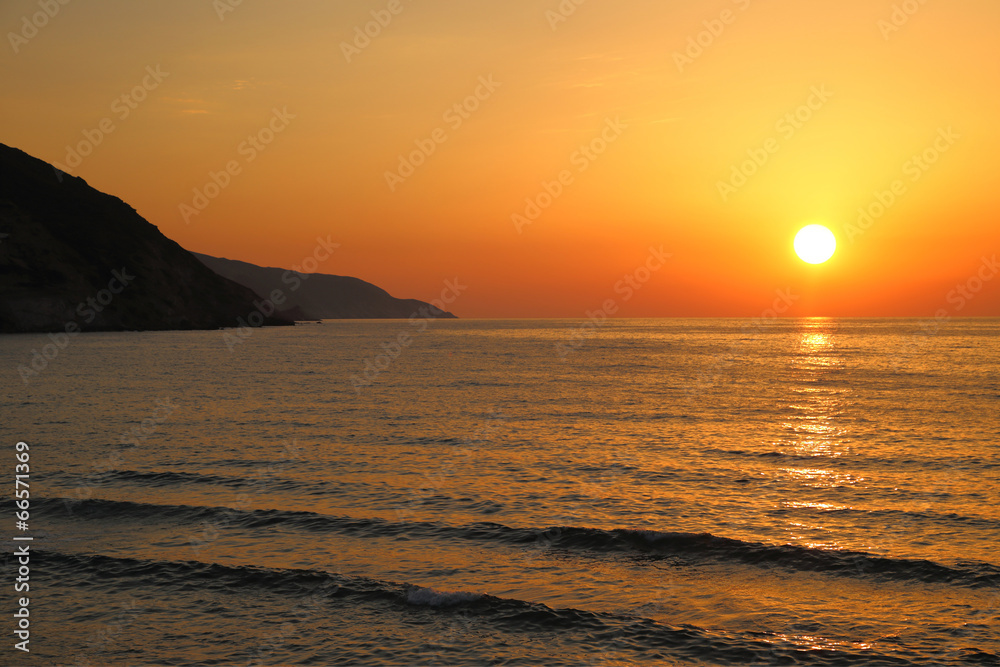 Sunset on the beach with distant mountains silhouettes