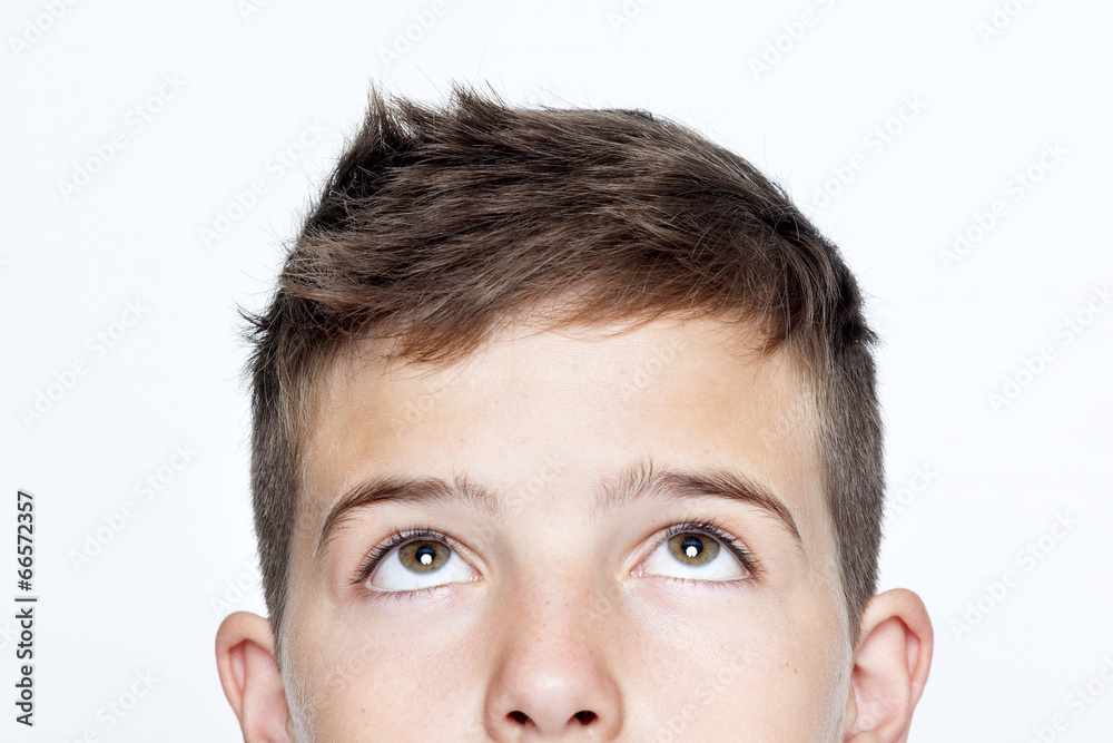 Obraz premium Bliska portret chłopca patrząc na szarym tle