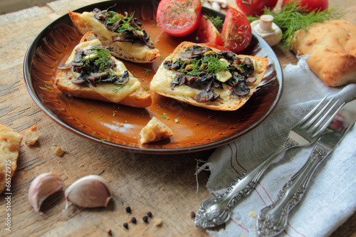 Plate with fresh bruschetta with mushrooms, cheese and garlic