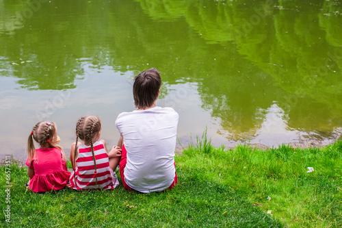 Happy father and little daughers relax by the lake photo