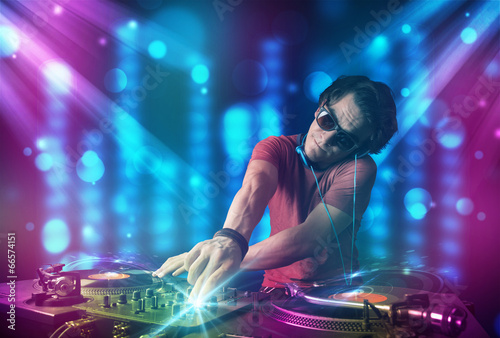Dj mixing music in a club with blue and purple lights © ra2 studio