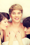 Handsome man lying in bed with two girls