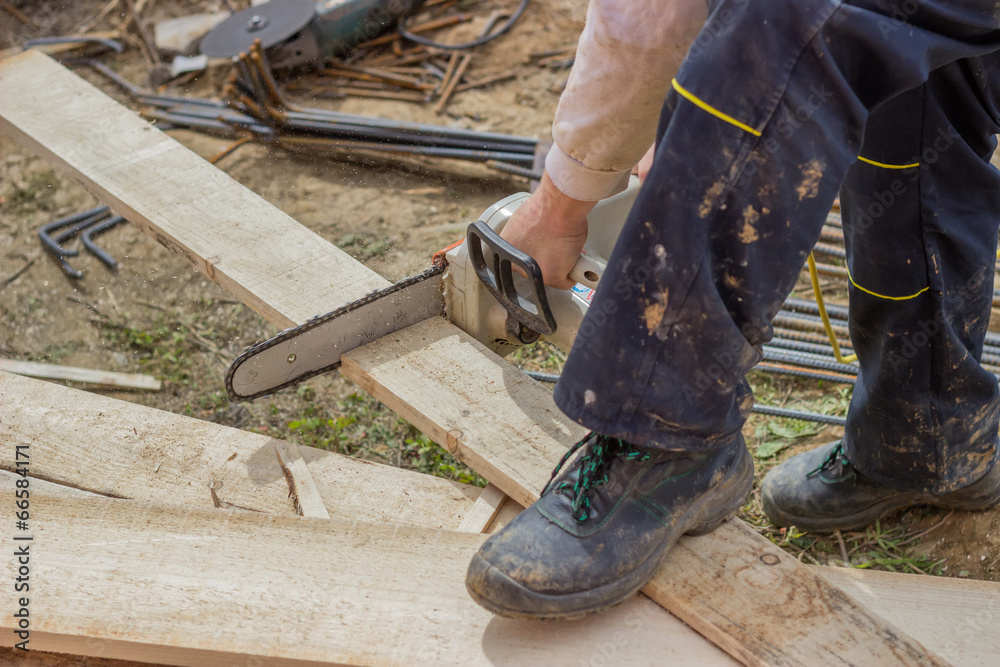 Builder worker cutting wooden plank with chainsaw Builder worker cutting wooden plank with chainsaw