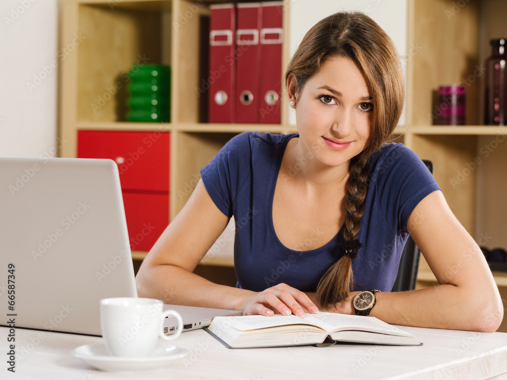 Beautiful woman reading and using a laptop Beautiful woman reading and using a laptop