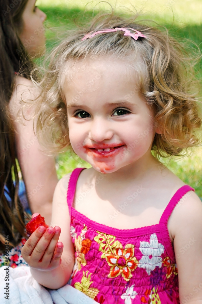 Blonde girl in summer dress eating strawberries. Blonde girl in summer dress eating strawberries.
