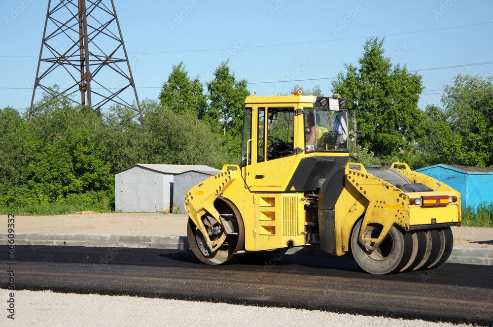 Yellow rolling machinery paving a road