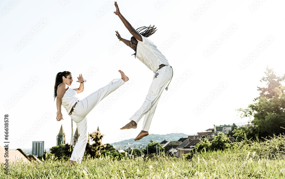 Pair of capoeira performers doing a kicking