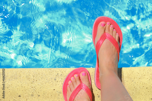 Female feet with flip flops by the pool © viperagp