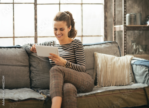 Smiling young woman using tablet pc in loft apartment