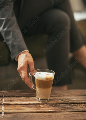 Closeup on business woman taking coffee latte from coffee table