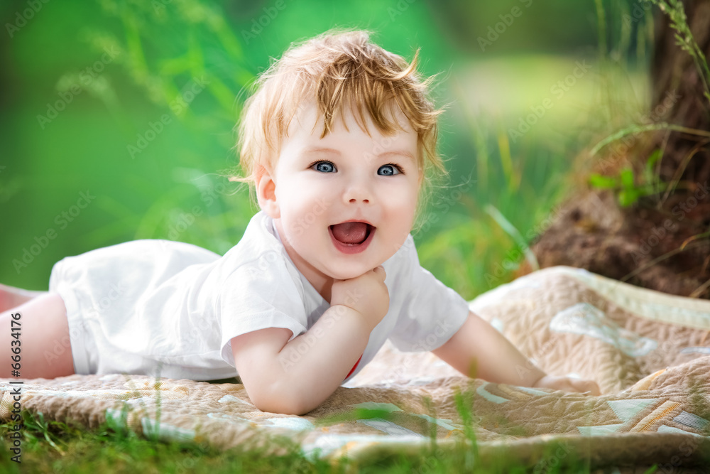 Happy little baby having fun in the park on the lake shore backg