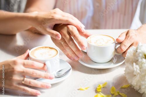 Women's and men's hands with wedding rings, at the cafe table wi