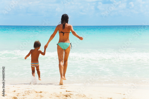 Child and woman holding hands on sea background
