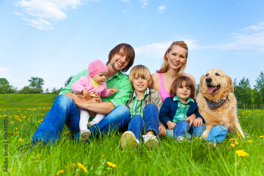 Smiling family sitting on green grass with dog Smiling family sitting on green grass with dog