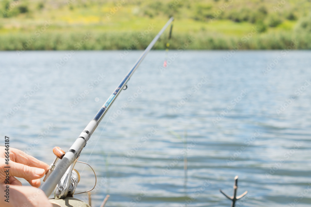 Man fishing on a lake with a spinning reel and rod Man fishing on a lake with a spinning reel and rod