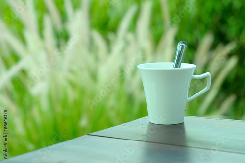 white cup of coffee with natural green grass background