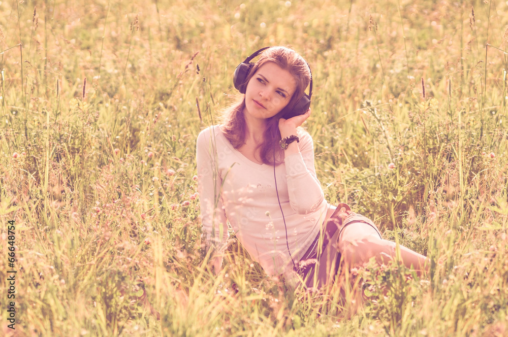 Background girl with headphones sitting in the grass in the fiel Background girl with headphones sitting in the grass in the fiel