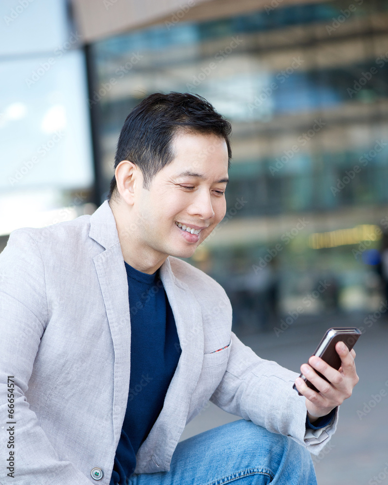 Asian man smiling with mobile phone Asian man smiling with mobile phone
