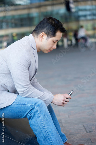 Asian man sitting with cellphone