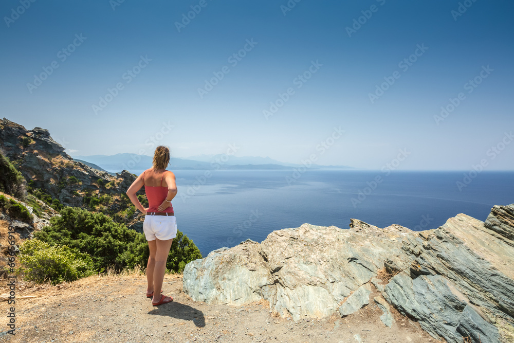 Fototapeta premium Woman looking out over Mediterranean coast from Cap Corse in Cor