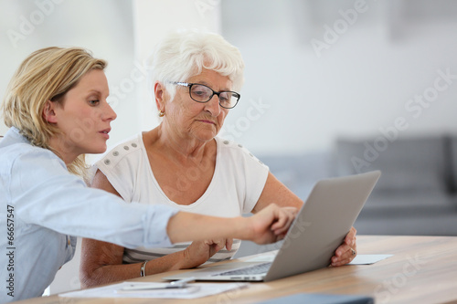 Homecarer with elderly woman using laptop computer