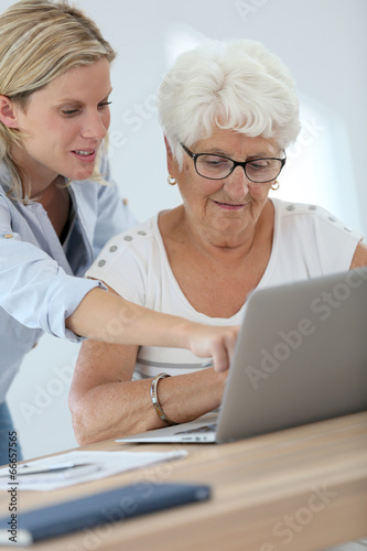 Homecarer with elderly woman using laptop computer