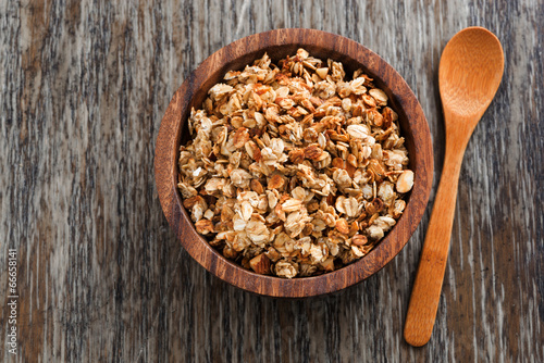 homemade granola in a wooden bowl and spoon, top view
