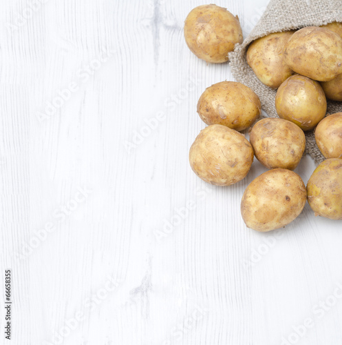 new potatoes in a sack on a white wooden  background