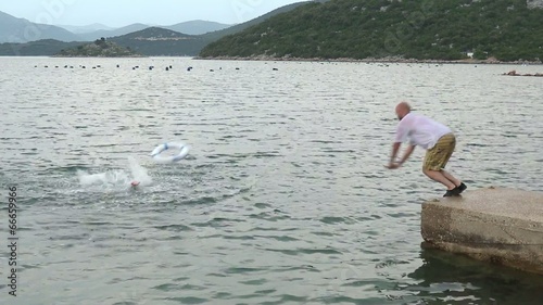 A young man drowning and a safeguard jumping in the water to rescue him