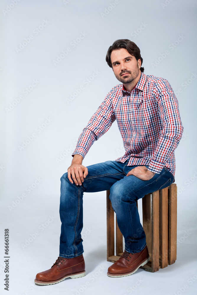 Handsome young man sitting on a wooden box Handsome young man sitting on a wooden box