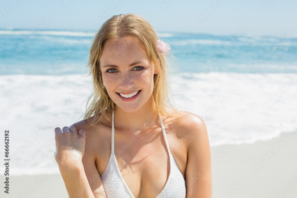 Beautiful blonde in white bikini smiling at camera on the beach Beautiful blonde in white bikini smiling at camera on the beach