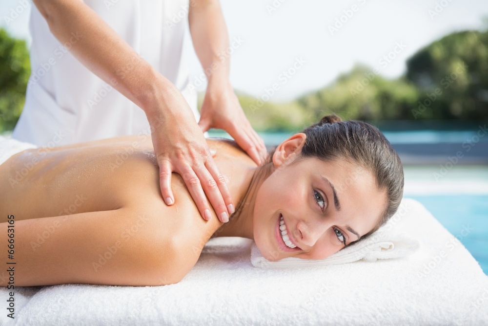 Obraz premium Happy brunette getting a massage poolside